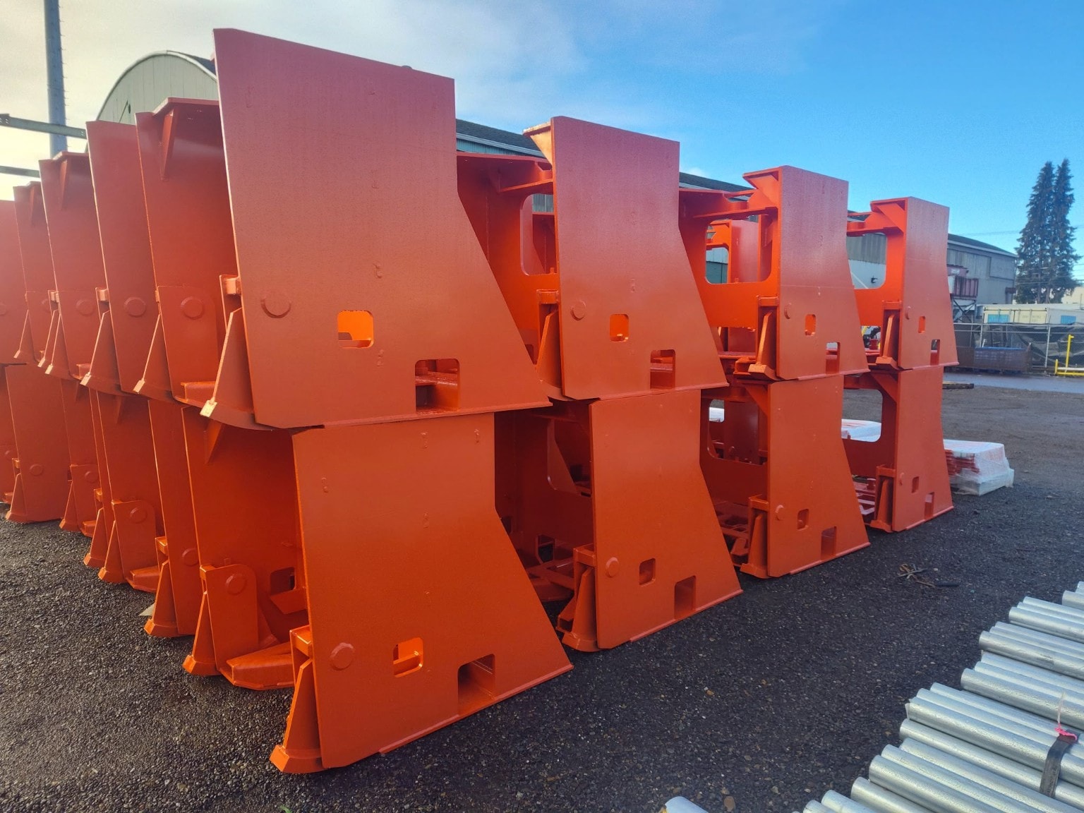 Orange-coated industrial structural components stacked outdoors after powder coating